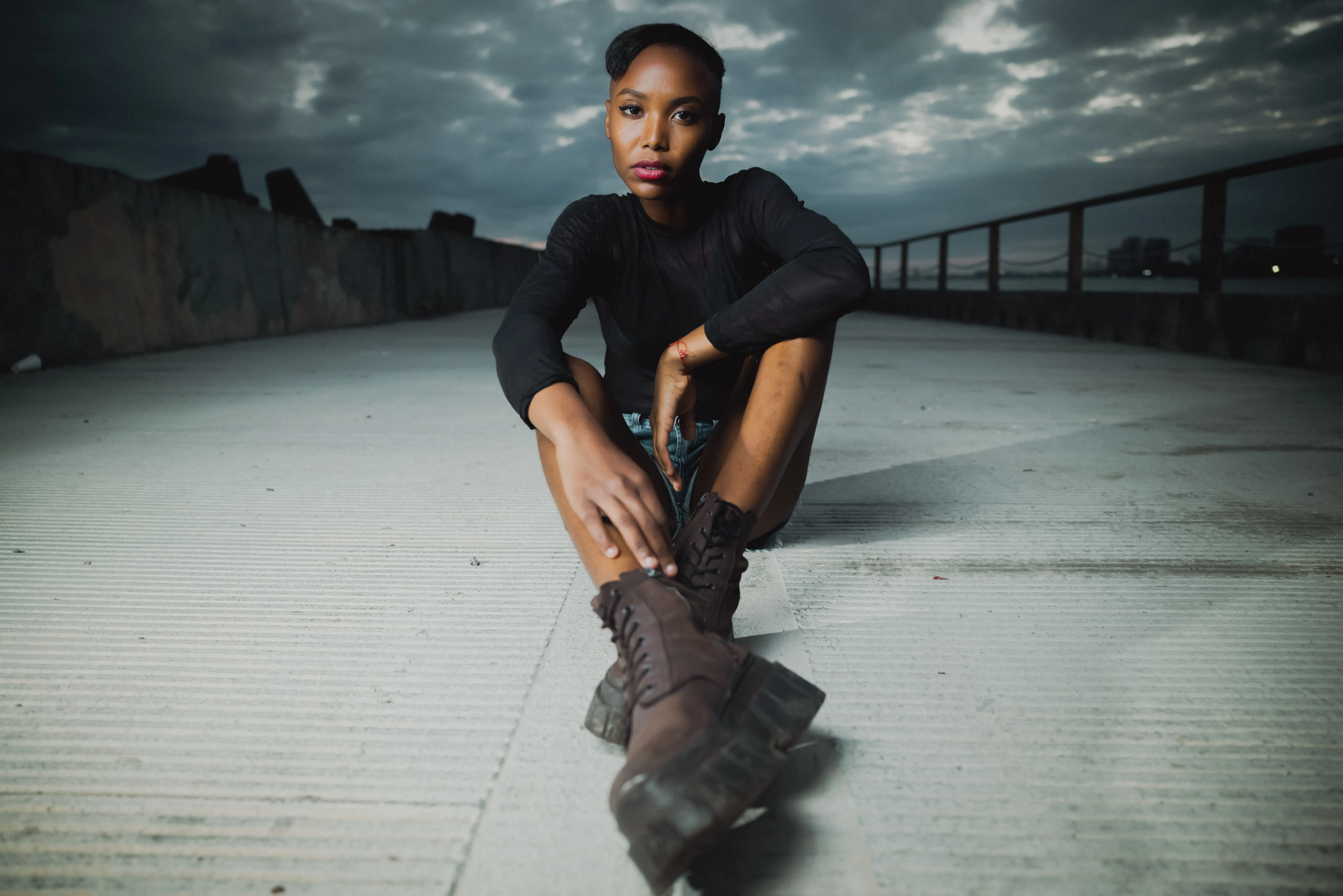 Urban portrait with dramatic sky Professional urban portrait in Santo Domingo: woman in black overcoat on rooftop with dramatic cloudy sky and metal railing