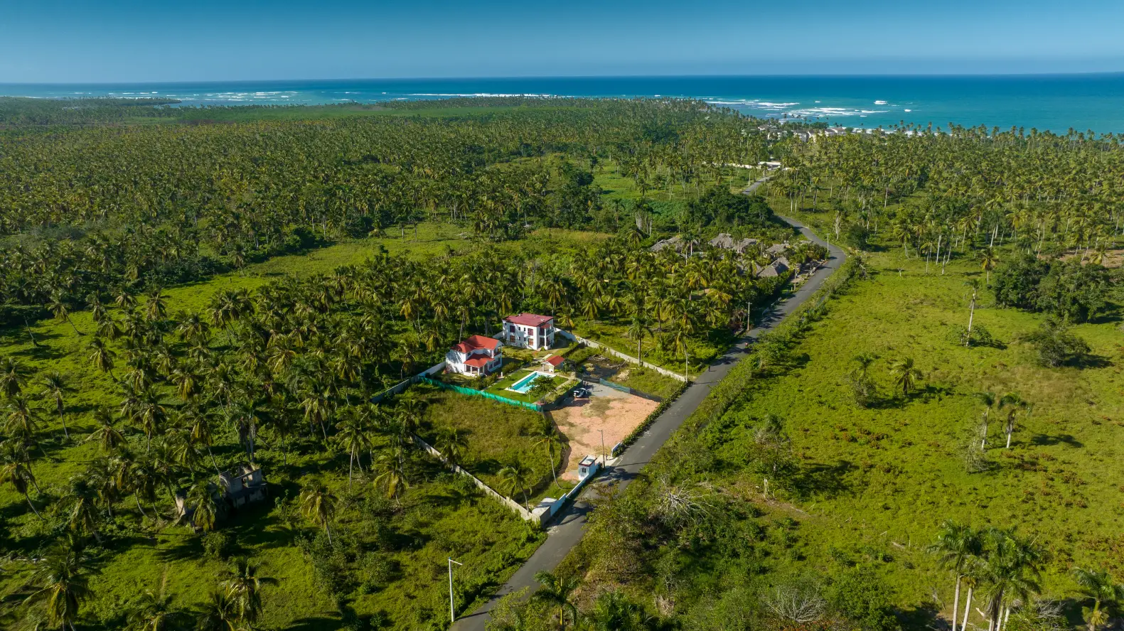Coastal Villa Aerial: Punta Cana from Above Aerial view of luxury villa with turquoise pool surrounded by palm trees and ocean in background, Punta Cana professional drone photography