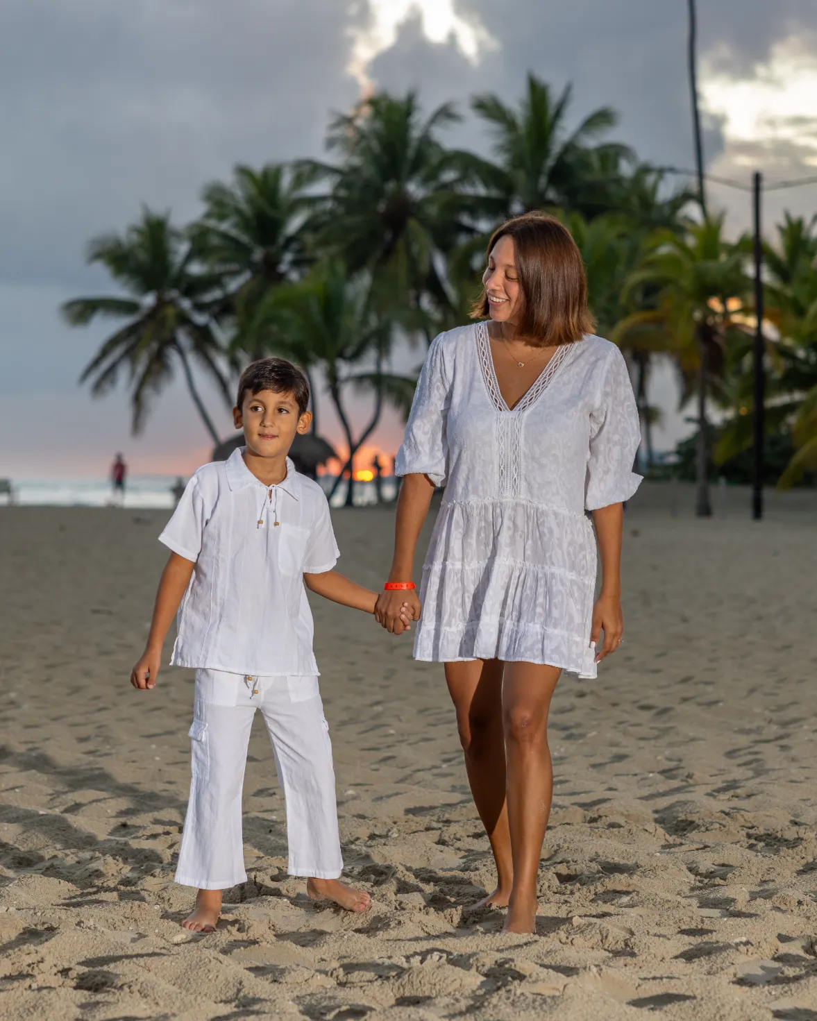Conexión familiar en la playa dominicana Madre e hijo caminan de la mano en la playa al atardecer en Santo Domingo, fotografía de familia con luz dorada